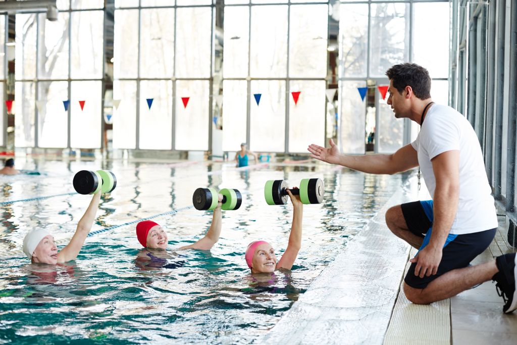 Wassergymnastik für Senioren: Trainer gibt Gruppe Anweisungen