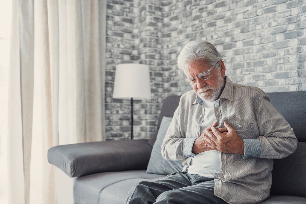 Erste Hilfe für Senioren: Ein Rentner fasst sich mit schmerzverzerrtem Gesicht ans Herz