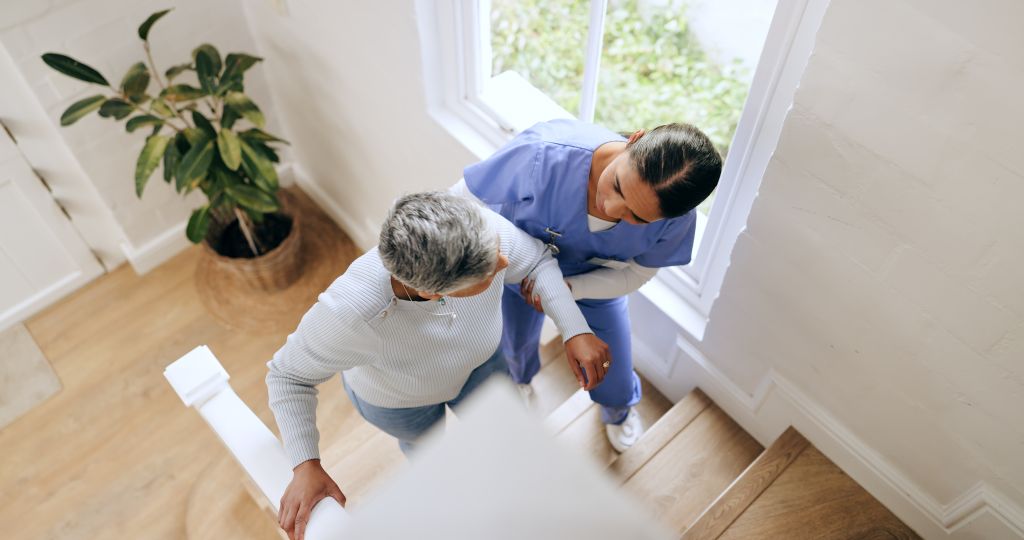 Eine Physiotherapeutin übt zusammen mit einer Seniorin das Treppensteigen