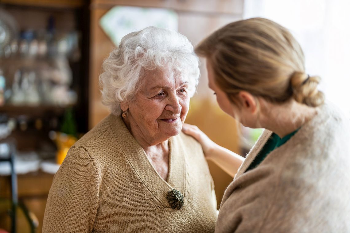 Eine junge Frau kümmert sich u eine Seniorin in ihrem Zuhause