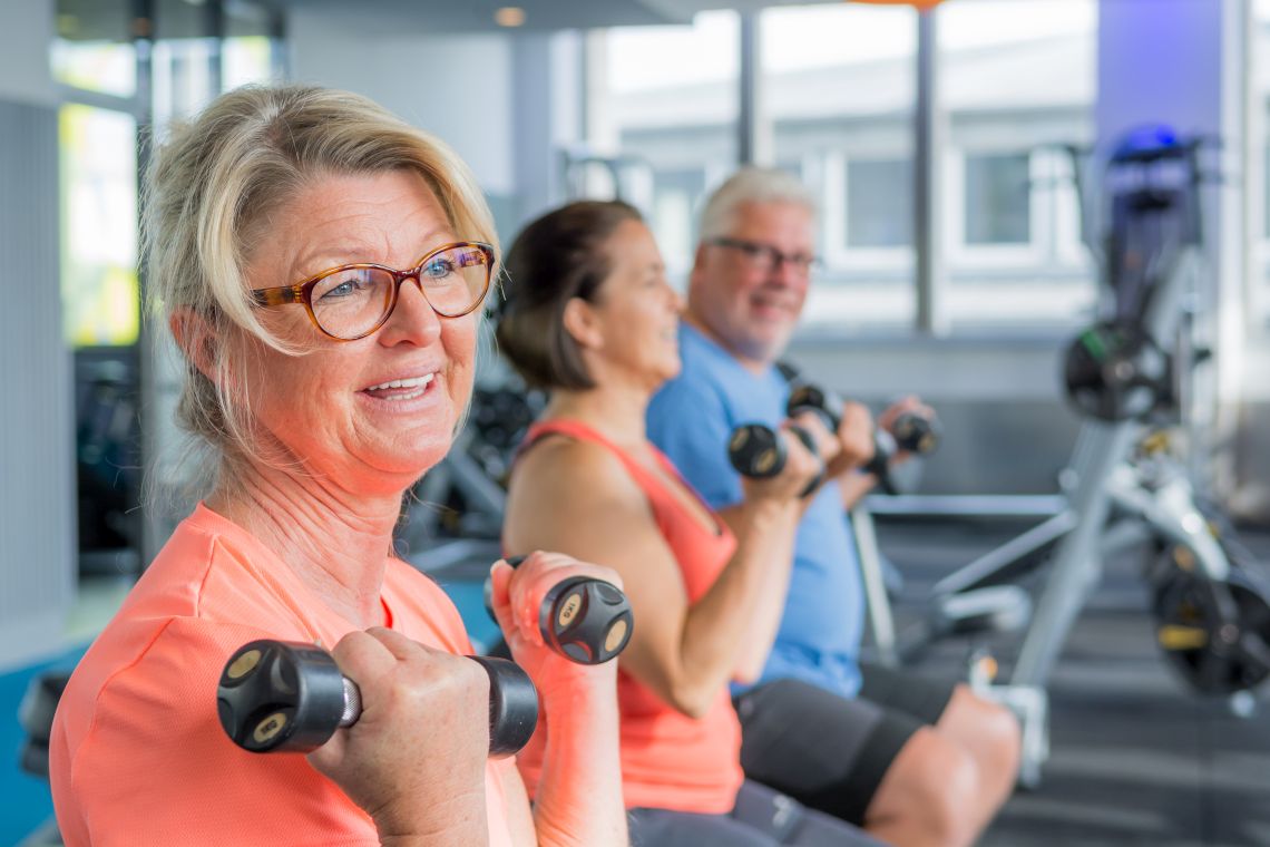 Drei ältere Menschen machen in einem Fitnessraum gemeinsam Übungen