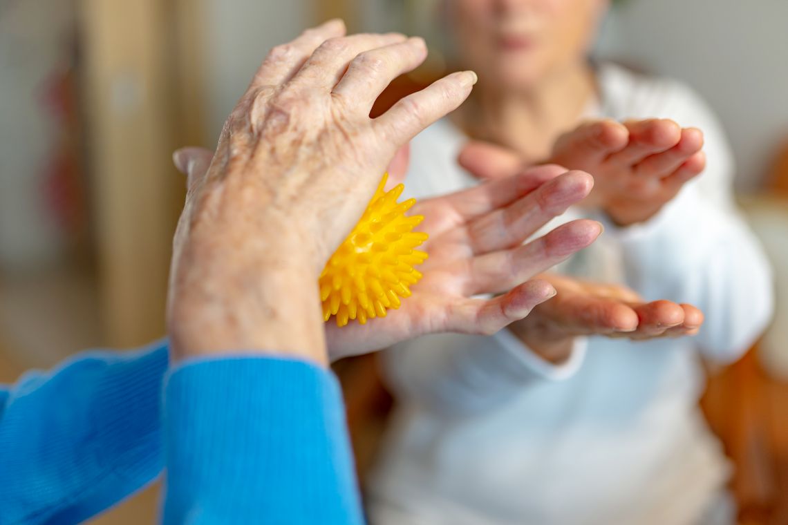 Eine Seniorin macht Übungen mit einem Igelball