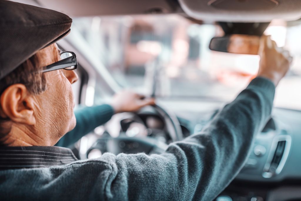 EU-Führerschein Senioren: Senior beim Autofahren, überprüft den Rückspiegel